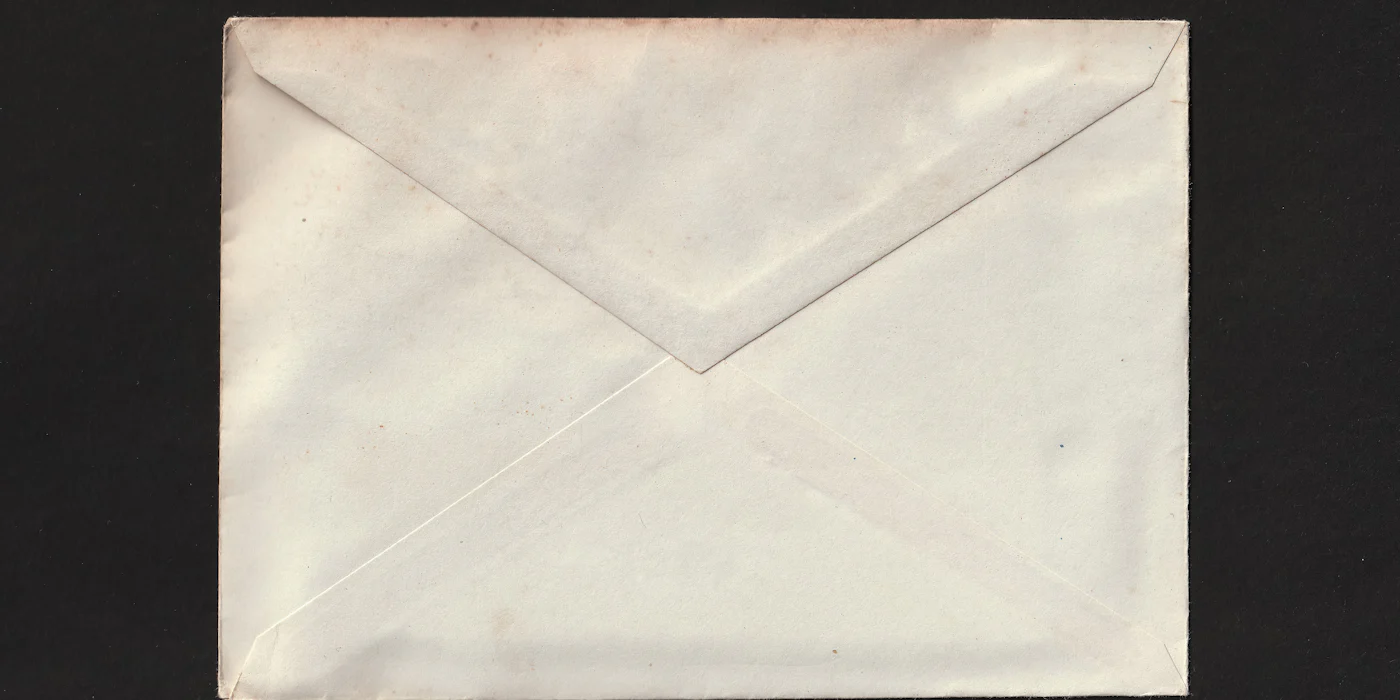 A worn cream paper envelope photographed on a black background